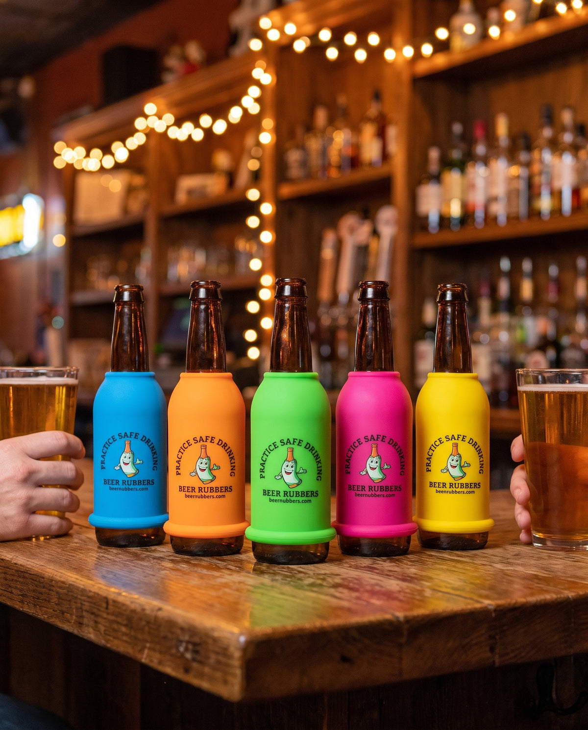 Colorful Beer Rubbers sleeves on bottles lined up on a bar table at night